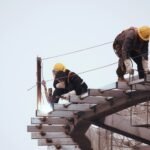 Two temporary construction workers working on a roof.