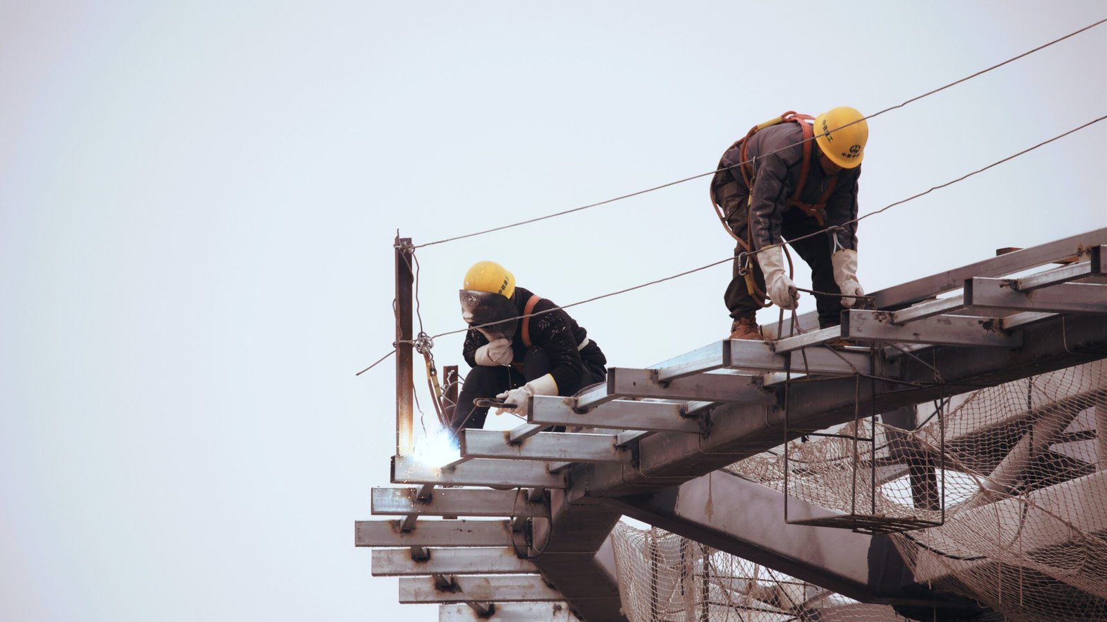 Two temporary construction workers working on a roof.