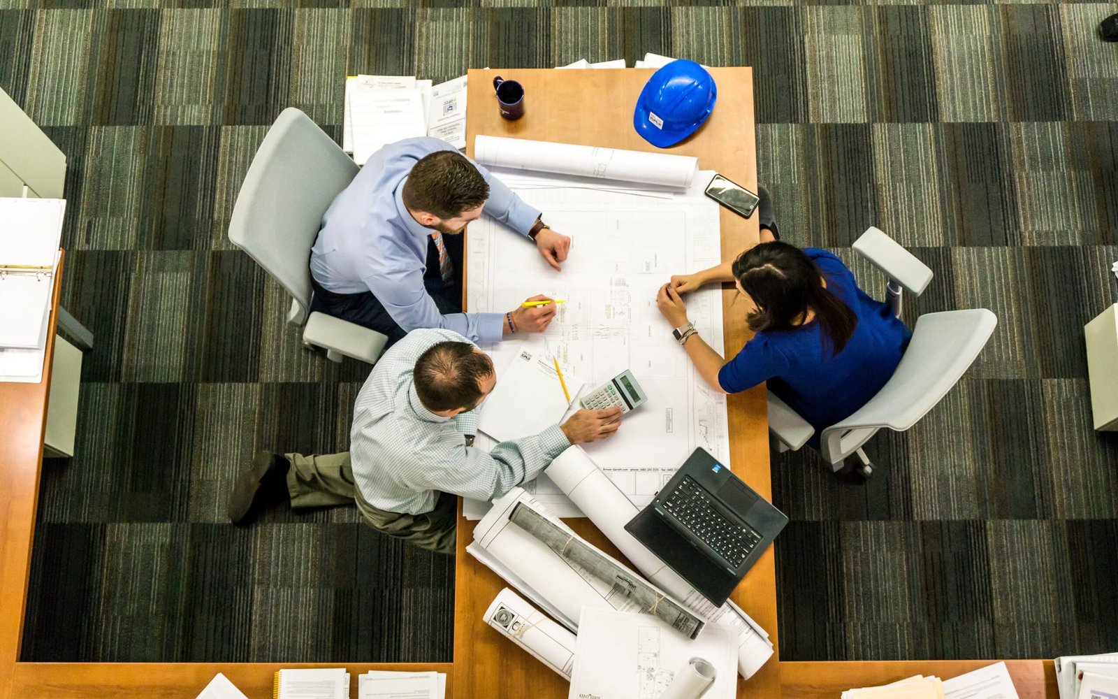 Site managers sitting around a table deciding whether to hire temporary or permanent construction workers