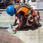 a man with a hard hat using a hammer on the ground to show why construction recruitment specialists are better than direct hiring